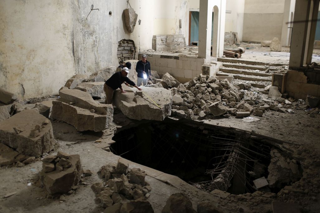Three people look at ruins