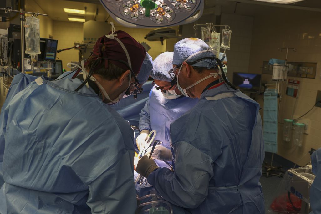 Doctors in scrubs gathered around a surgery table