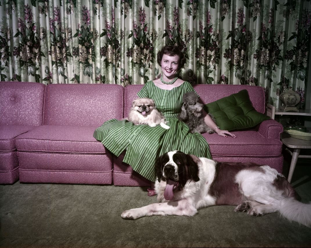 A young Betty White with three dogs