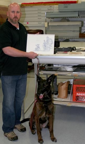 Photo of man holding up drawing with dog