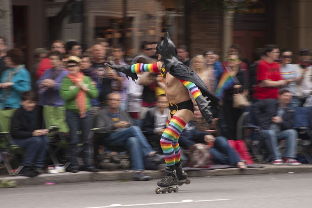 a person dressed up as Batman roller skates during a Pride parade