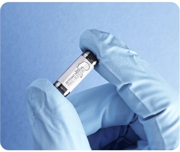 a blue gloved hand holds a pill-sized electronic capsule