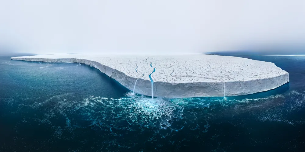 The Austfonna Ice Cap, ranked as the third largest in the world, is a breathtaking expanse nestled on Nordaustlandet Island within Norway's Svalbard archipelago. Covering an astonishing 8,000 square kilometers, this icy giant is confronting a troubling fate, primarily due to the relentless march of global warming. Its rapid thawing is a sobering contributor to the escalating threat of rising sea levels, a somber reminder of the perilous state of our planet's climate.

During my recent expedition to the Austfonna Ice Cap, I had the profound privilege of capturing a truly extraordinary moment—an image that encapsulates the very essence of its vulnerability. While I had visited this location on prior occasions, this time was uniquely disheartening. In June, the sea ice that typically guards this immense ice cap had already receded, granting us access by ship. This year, the onset of melting arrived earlier than expected, giving birth to a mesmerizing waterfall—a testament to nature's relentless transformation.

As I gazed upon the enchanting scenery, it was impossible to ignore the harsh reality that this once-mighty ice cap is steadily dwindling, and its disappearance seems inevitable within a few short years. The image I captured is a composite of 26 individual frames, meticulously stitched together to immortalize the transient beauty of this natural wonder. It serves as both a testament to the awe-inspiring grandeur of our planet and a poignant reminder of the urgent need to address the pressing issue of climate change.