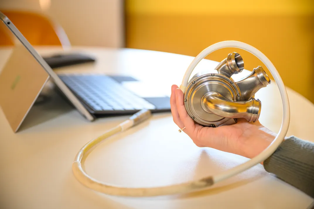 Metal gadget in a woman's hand next to a computer