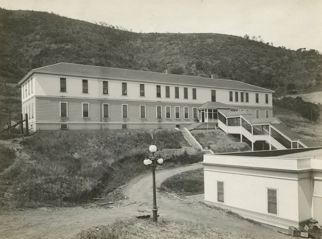 Long two-story building set on the side of a hill. Black-and-white archival photo.