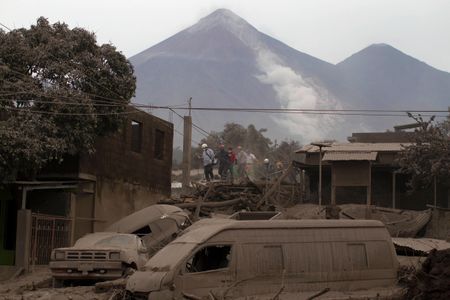 Rescue workers walk on rooftops in Escuintla, Guatemala, Monday, June 4, 2018, blanketed with heavy ash spewed by the Volcan de Fuego, or "Volcano of Fire."