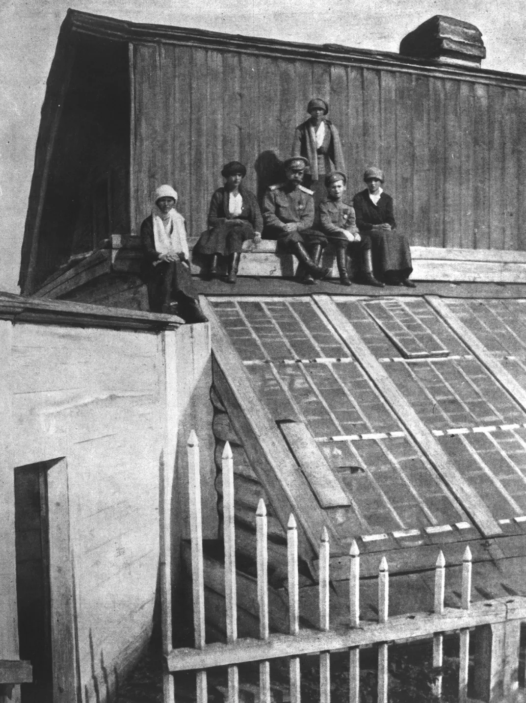 L to R: Olga, Anastasia, Nicholas, Tatiana (standing), Alexei and Maria sitting on the roof of a greenhouse in Tobolsk in 1917