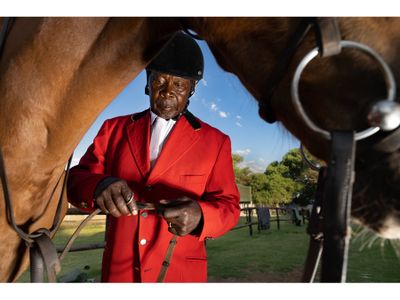 Wearing his national title show jumping jacket, Mafokate checks the reins before mounting his horse at a local competition in the township.