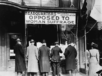 Men looking at material posted in the window of the National Anti-Suffrage Association headquarters, around 1911.