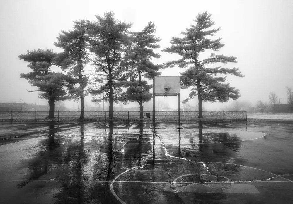 Here you see a basketball court at a local playground. A rainy, foggy day it was and 
no one is out playing. I am not a fan of bouncing a basketball on a wet court.