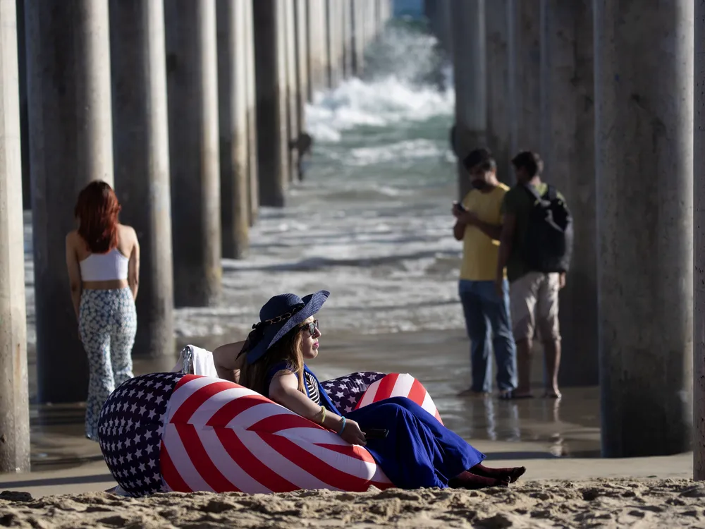 A person sitting in an American flag chair on the beach