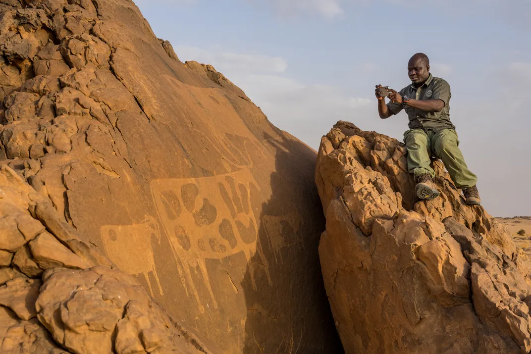 Djimet Guemona, a Chadian archaeologist, documents a prehistoric petroglyph—a stylized but telltale representation of cattle.