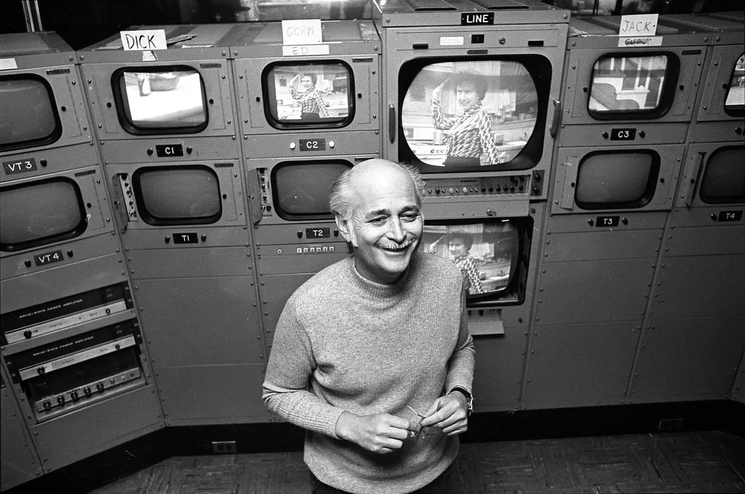 Norman Lear stands in front of camera monitors