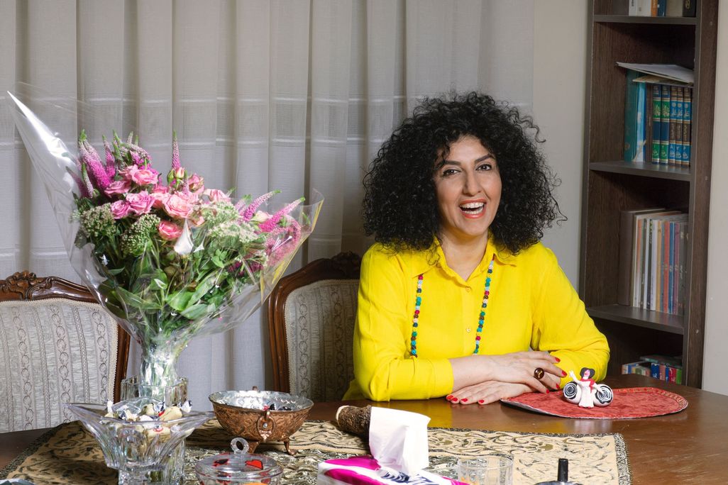 Smiling woman wearing a yellow shirt next to a bouquet of flowers