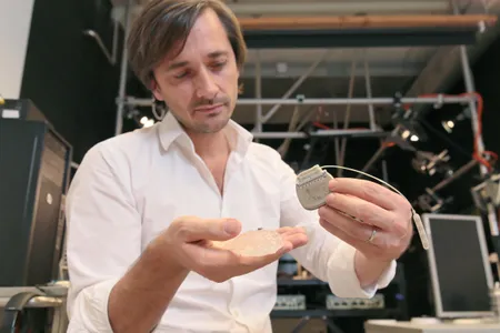 Grégoire Courtine, an author on the new study, holds a silicon model of a primate’s brain, a microelectrode array and a pulse generator. The brain-spine interface consists of elements like these. 