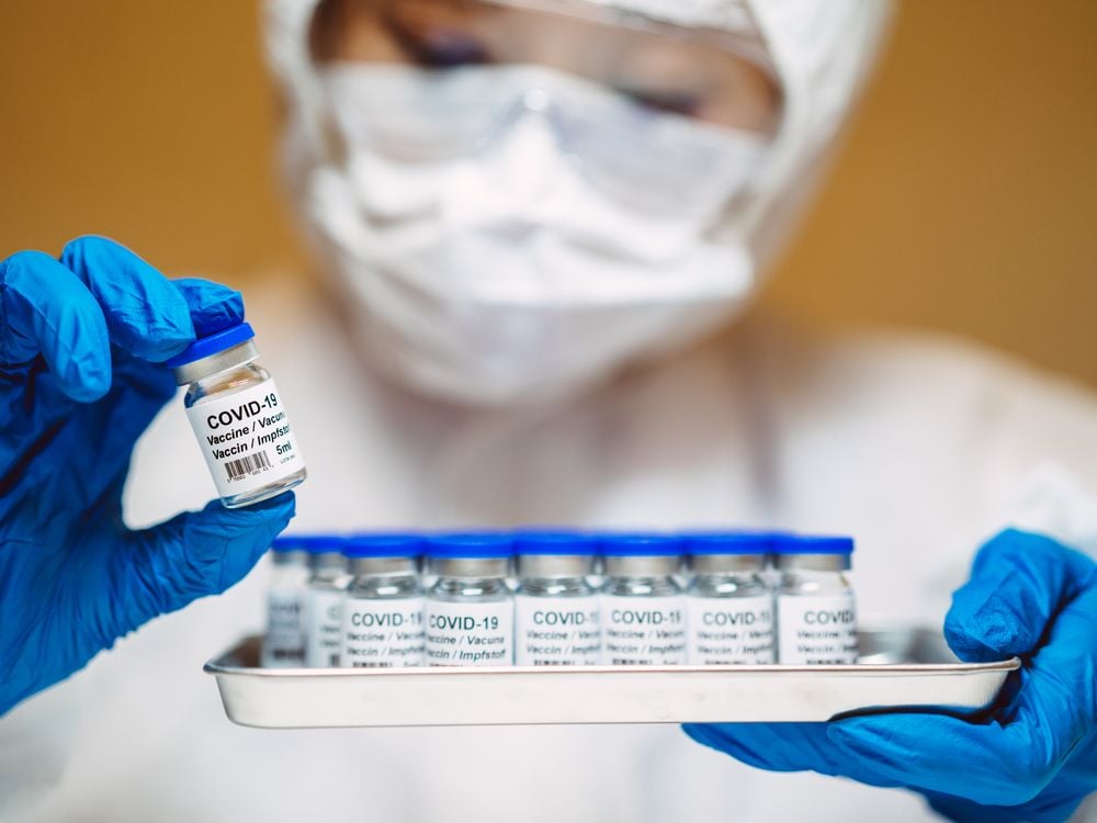 A staged stock image of a healthcare worker holding a tray of generic Covid-19 vaccines