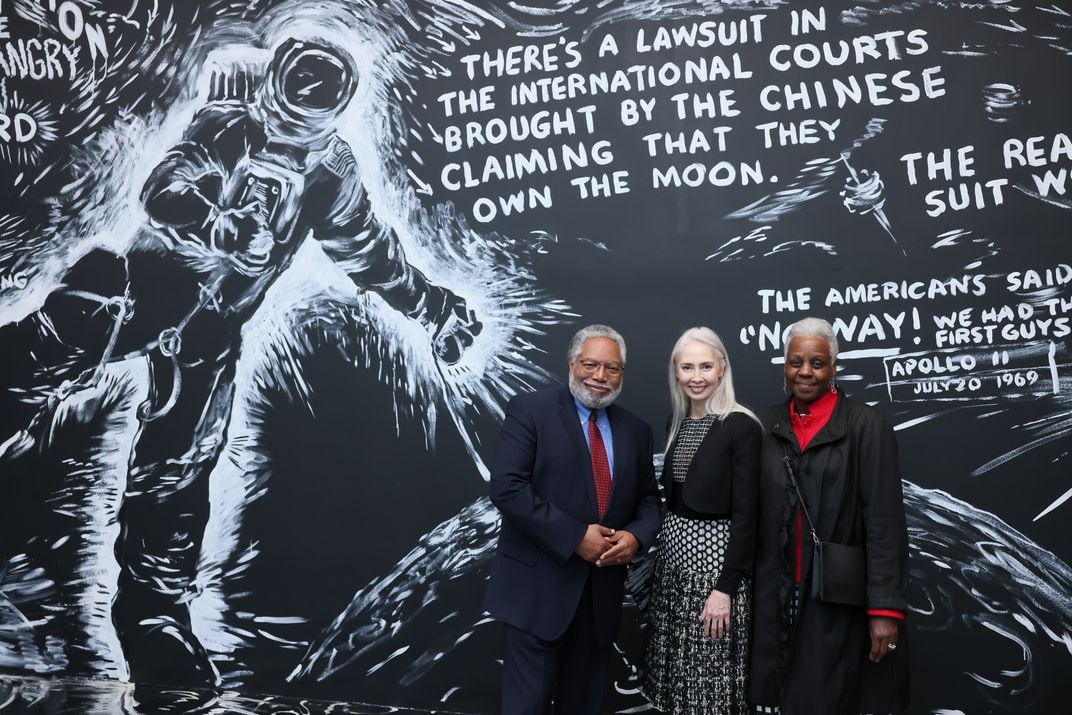 Secretary Bunch, Melissa Chiu, and Maria Marable-Bunch stand in front of a black-and-white full wall display at the Hirshhorn Museum