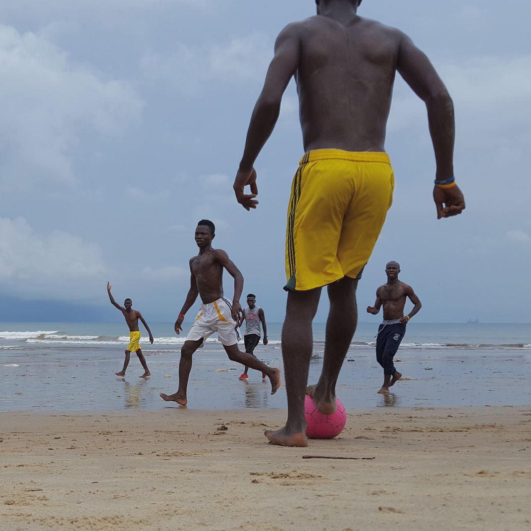 a group of people play soccer on the beach