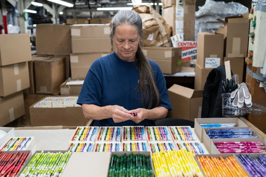 a woman sorts through boxes of colored pencils