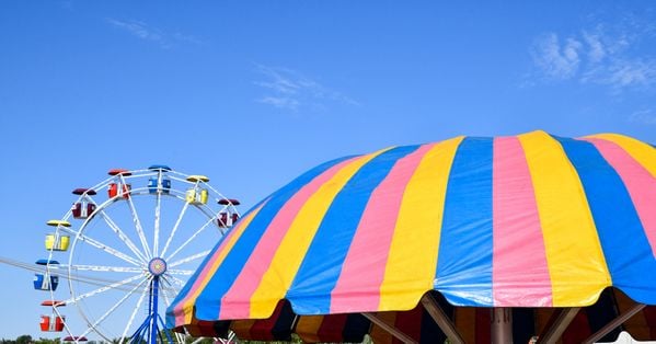 Colorful tent and amusement park ride under blue sky thumbnail
