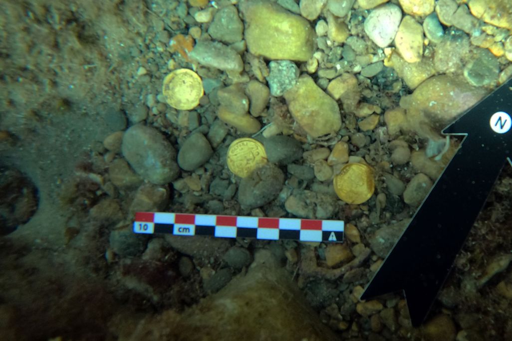 coins lying amidst small stones underwater