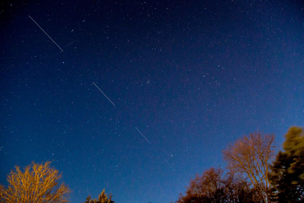 A dark blue night sky, with pinpricks of stars and long streaks where the satellite traveled through the shot