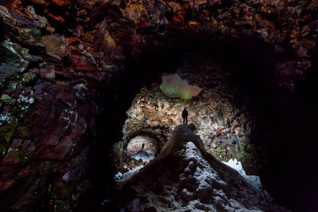 This image was taken while exploring a 1300m lava cave in Iceland. In some areas the roof has caved in, so snow piles up in the winter time and creates these snow peaks. The aurora at its peak gleams through the roof of the cave and despite only taking up a small portion of the photo, it remains the focal point.	