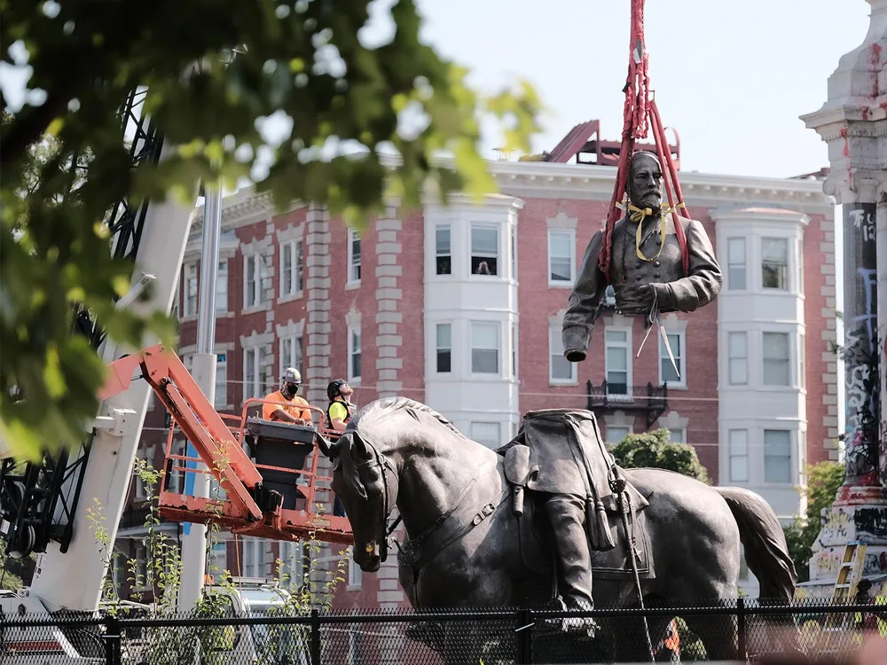A view of a crane lifting the top of the sculpture, including Lee's torso and arms, off of his legs and horse below