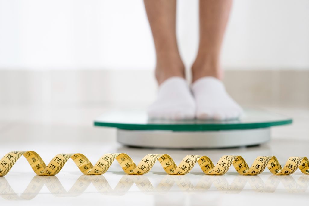 the feet of a person standing on a scale with a measuring tape on the floor