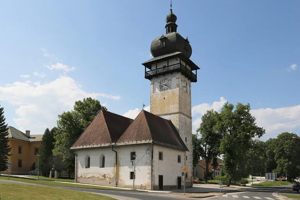 One tall tower with a domed black roof, next to two small buildings 