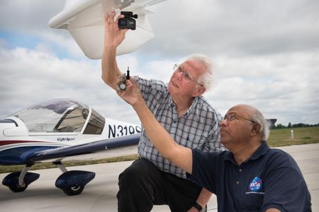 Rafat Ansari of NASA Glenn (right) helps attach a camera to a volunteer pilot's aircraft.