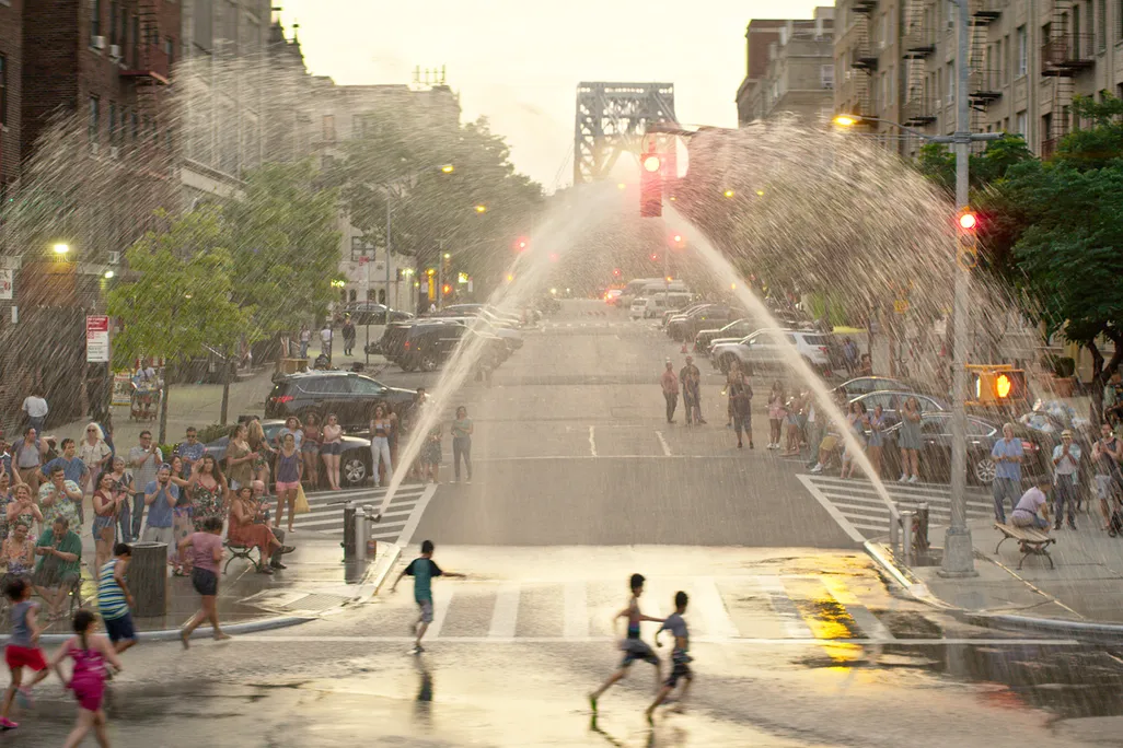 Children run through sprinklers in Washington Heights