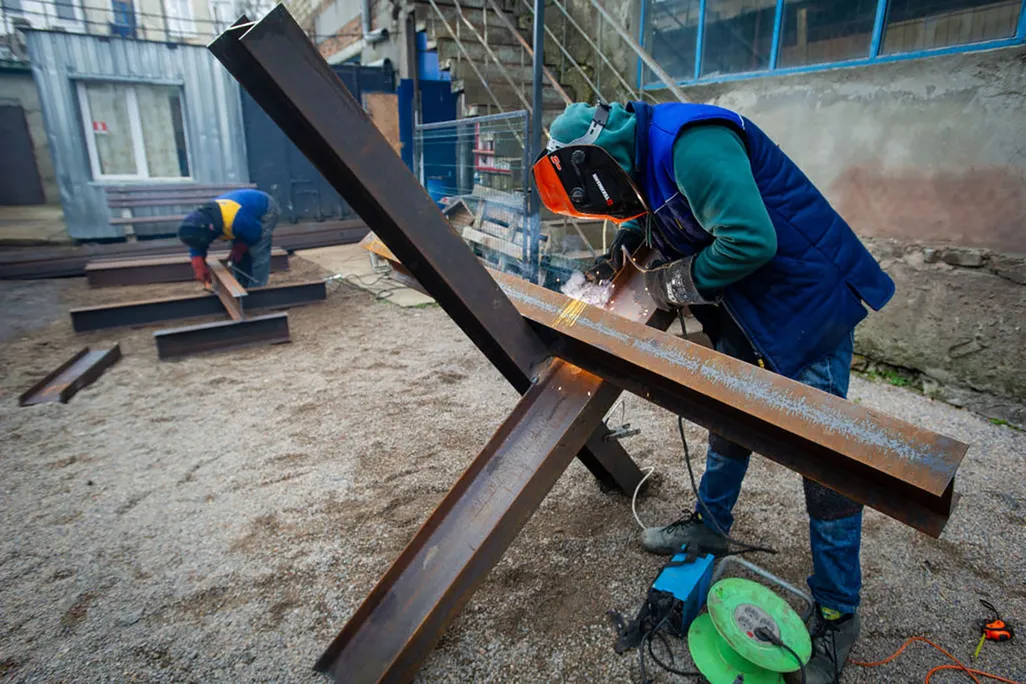 2 people in protective gear welding together steel beams