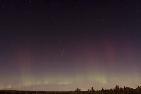 A Draconid meteor streaks across the sky as the northern lights glow, as seen from north of Stockholm on October 8, 2011.