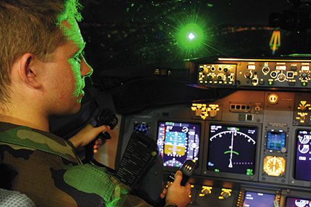 Air Force Second Lieutenant Paul LaTour is illuminated by a green laser during a landing in a Boeing 737 flight simulator at the FAA center in Oklahoma City. The Air Force and FAA worked to determine what level of laser exposure is safe for pilots.