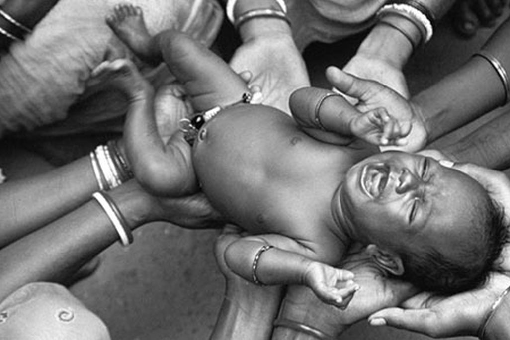 newborn held by relatives and neighbors