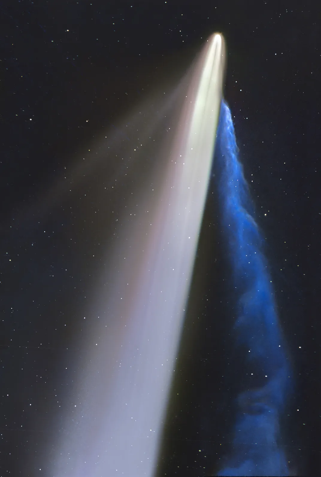 a bright comet travels upward, trailing two bright tails—one white and one blue