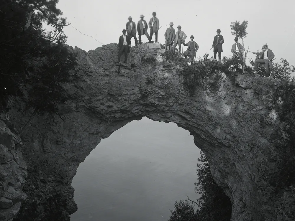 Visitors pose atop Arch Rock, a geological formation on Mackinac Island