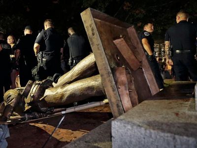 Police stand guard around the Confederate statue Silent Sam after it was toppled by protestors at the University of North Carolina at Chapel Hill. 