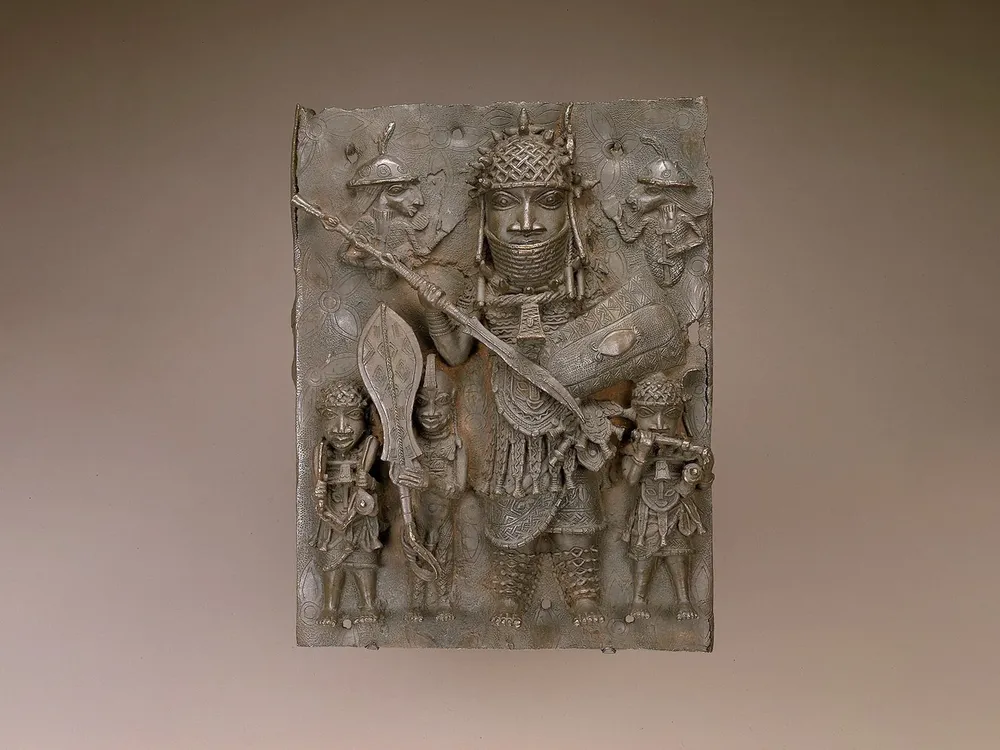 A view of a bronze plaque depicting an oba, or king, with a spear and sword standing over smaller figures beneath him