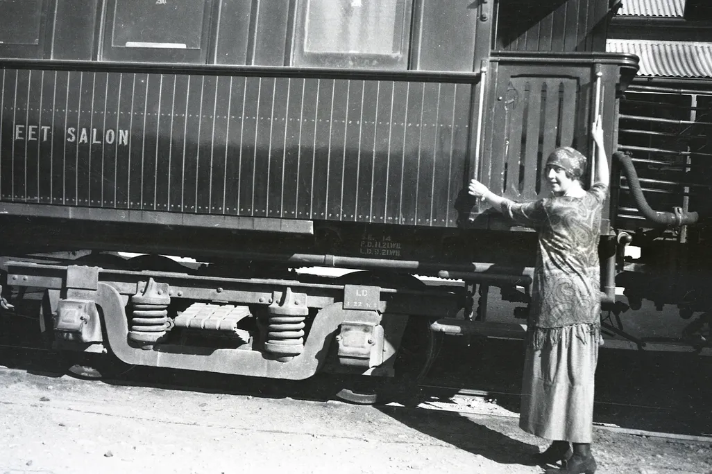 A woman poses next to a train