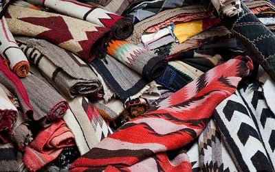 A potential buyer must carefully inspect the rugs at the Navajo rug auction.