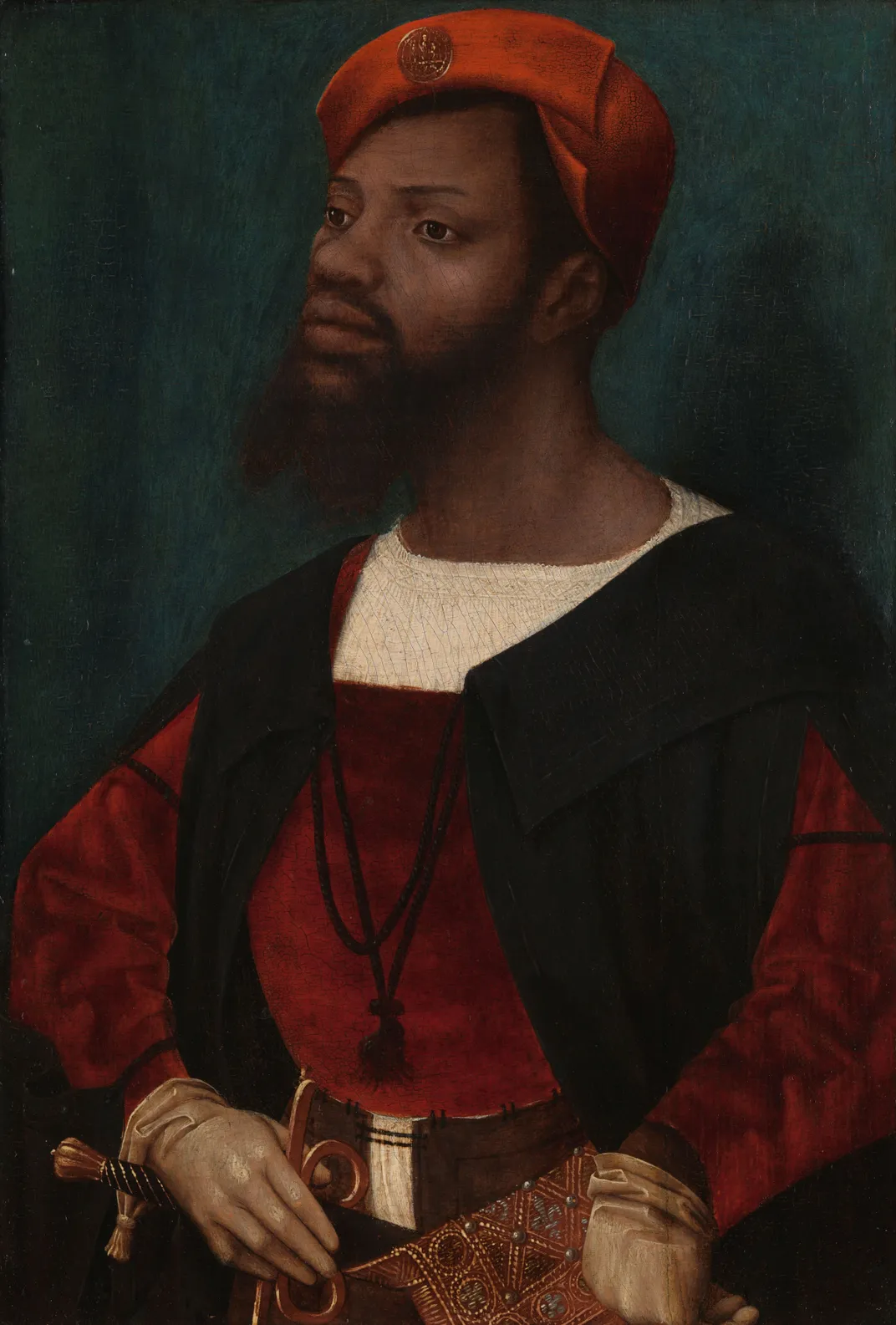 A portrait of a Black man with a beard, in elegant costly dress and posed with his chin raised in a confident position