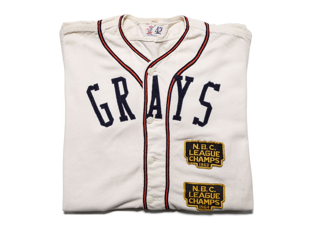 White, folded baseball jersey with text across the chest that reads GRAYS.