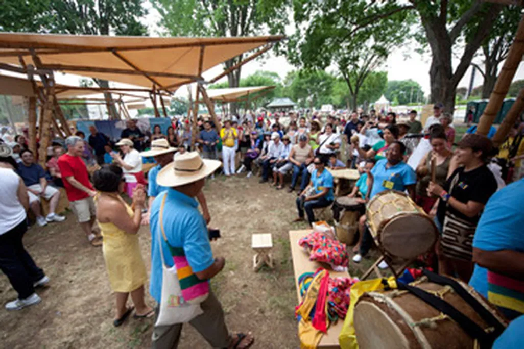 Visitors and artists interact under the guadua (bamboo) tents in the Colombia program area.