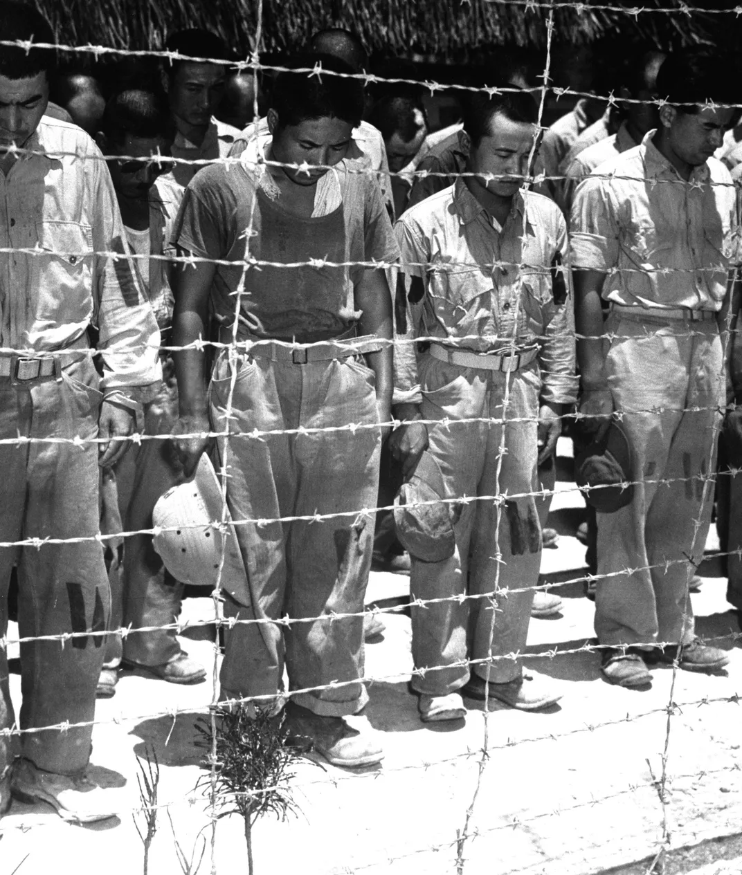Japanese POWs in Guam bow their heads after hearing Emperor Hirohito's announcement of Japan's unconditional surrender.