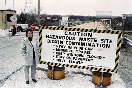 Marilyn Leistner, who was the last mayor of Times Beach, stands next to a caution sign erected in front of the town in 1991, not long before the town was bulldozed and buried.