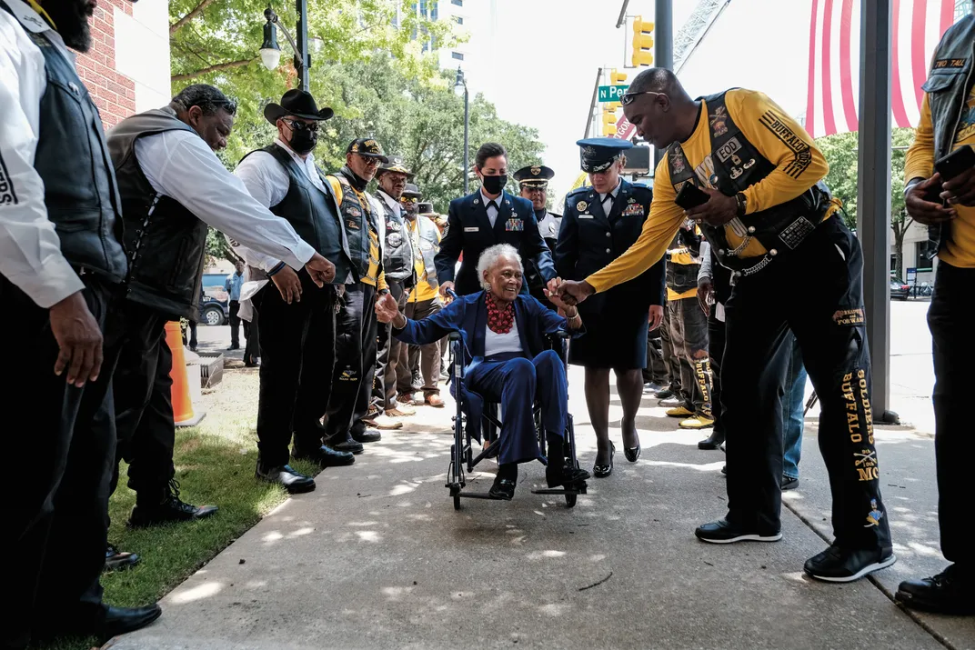 a woman veteran rolling in her wheel chair receives a standing ovation from military veterans