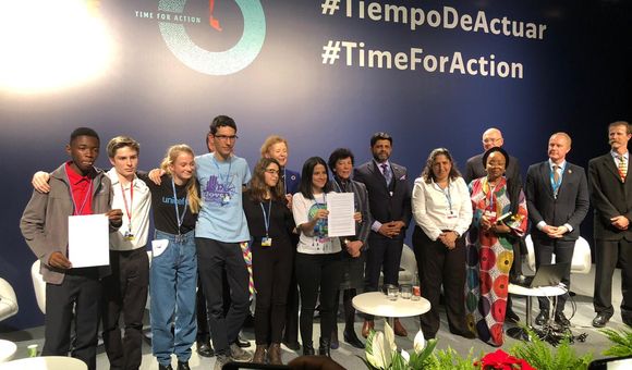 Sara Cognuck (center) shows the Declaration on Children, Youth and Climate Action.