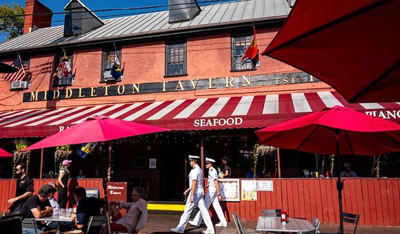 OPENER - Two U.S. Navy officers stroll past the sunlit Georgian splendor of Middleton Tavern in Annapolis, Maryland. Horatio Middleton established the tavern here in 1750. Today, visitors can order classic Chesapeake seafood, including oysters and rockfis
